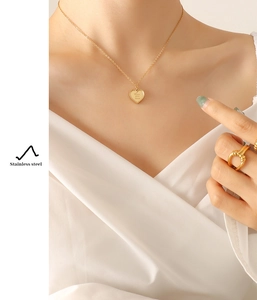 Gros plan du pendentif cœur doré avec gravure Love you more sur chaîne en acier