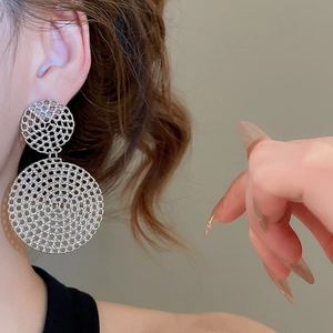 Close-up of silver mesh double disc drop earrings shown on a model for scale