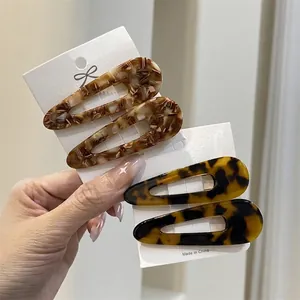 Set of four teardrop acetate hair clips in amber and tortoiseshell on a display card