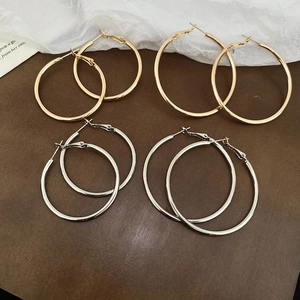 Close-up of classic gold and silver hoop earrings in large and small sizes on a dark background