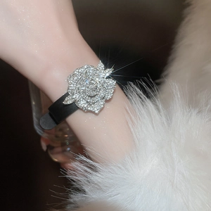 Nahaufnahme eines glitzernden Strass-Rosenarmbands mit schwarzem Band am Handgelenk