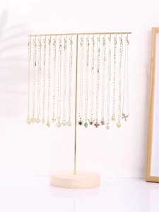 Detail of T-bar jewelry stand with round wooden base displaying various gold necklaces