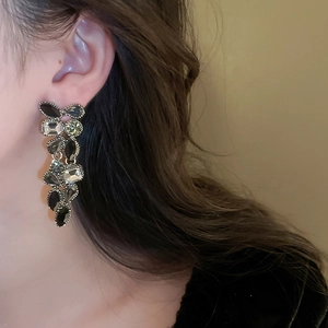 Close-up of elegant gold tassel earrings with grey and clear crystals on a female model