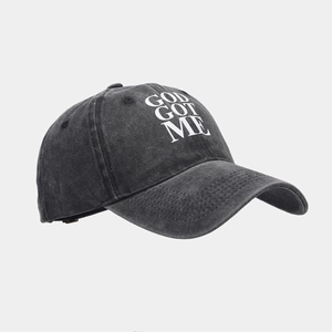 Dettaglio del cappello vintage in cotone nero lavato con scritte gotiche bianche GOD GOT ME
