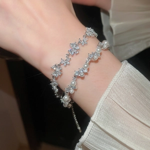 Close-up of elegant butterfly zircon and pearl bracelets on woman's wrist