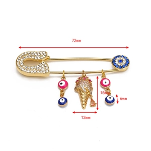 Detail view of gold-plated evil eye safety pin brooch showing 72mm length and charms