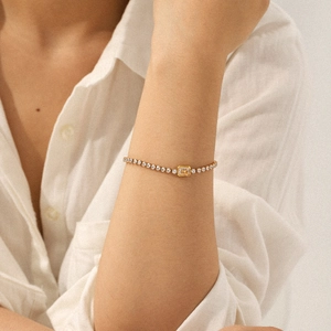 Bracelet tennis doré élégant avec zircon rectangulaire porté au poignet d'une femme
