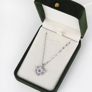 Detailed macro view of heart-shaped shell pendant necklace in a green velvet jewelry box