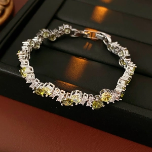 Macro detail of silver zircon bracelet with green gemstones on black leather display