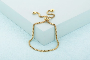 Macro shot of gold snake chain bracelet with adjustable sliding clasp and bead details