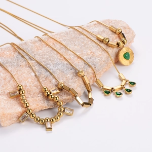 Golden necklaces with green cat-eye stone and zircon pendants on natural stone background