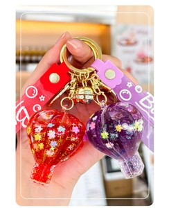 Detail of red and purple hot air balloon keychains with glitter and gold bells