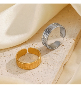 Macro detail of gold and silver stainless steel rings with textured stripe on stone surface