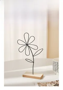 Detail of minimalist black metal flower sculpture with a natural wooden base decor