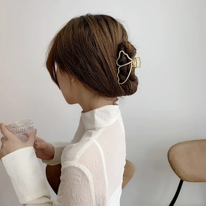 Golden butterfly metal hair claw clip worn on model's dark brown hair with elegant styling