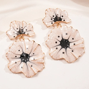 Detailed close-up of beige and black enamel ginkgo flower earrings with gold edges
