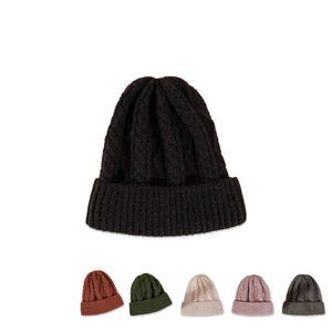Detail of multi-color knit beanies showing thick cable knit patterns and folded cuffs