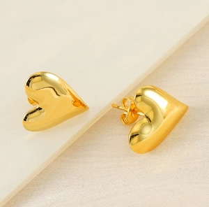 Detailed view of polished heart-shaped gold studs with classic butterfly backings