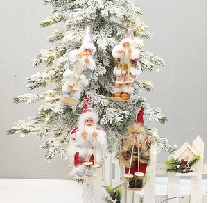 Close-up of four skiing Santa plush ornaments hanging on a snowy Christmas tree branch