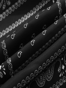 Détail du tissu de la veste noire avec motifs paisley et imprimés smiley face