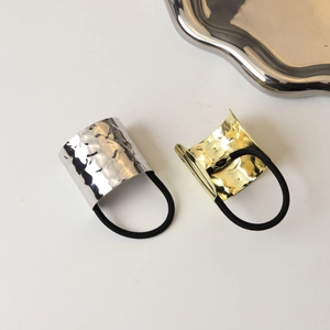 Detail of minimalist gold and silver textured alloy hair ties with thick black elastic bands