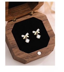 Macro detail of S999 silver bow earrings with zircon in a premium wooden gift box