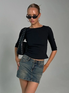Slim fit black crewneck knit top paired with denim skirt and retro shoulder bag
