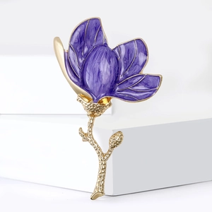 Exquisite purple enamel magnolia flower brooch with golden stem on a white pedestal