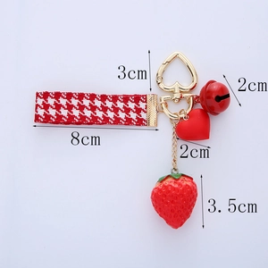 Detailed dimensions of strawberry keychain with red houndstooth strap and heart charm
