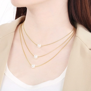 Close-up of triple-layered gold snake chain necklace featuring elegant white round pearls