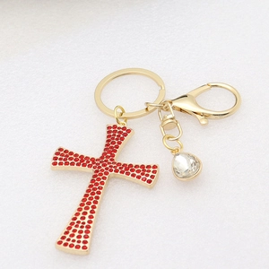 Detail of a golden cross keychain with red rhinestones and a clear crystal drop pendant