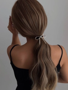 Macro detail of a silver metallic irregular bow hair tie on a low-light backdrop