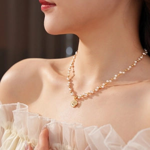 Detail view of a pearl and gold bead necklace with an eight-pointed star pendant on model