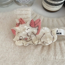 Detail of Marie Cat hair clip with pink bow on beige knit fabric background