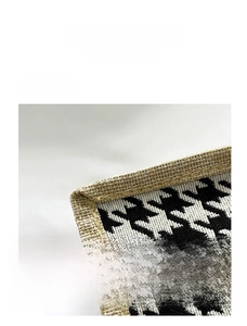 Detail of woven houndstooth fabric with beige jute edge and yellow stitching on handbag