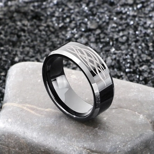 Polished silver and black tungsten ring with Celtic knot patterns on a natural rock