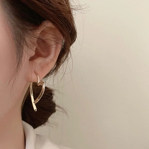 Detailaufnahme eines Models mit minimalistischen goldenen Herz-Creolen Ohrringen