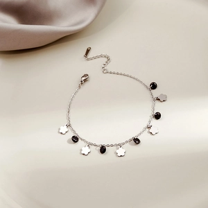 Close-up of silver chain bracelet with flower charms and polished black oval beads