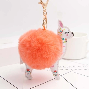 Orange faux fur alpaca keychain with floral pattern and golden hardware on white desk