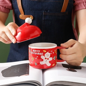 Red Christmas ceramic mug with Santa hat lid and festive gingerbread man illustration