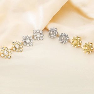Elegant gold and silver stud earrings with pearls and crystals on champagne silk background
