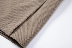 Macro de la manche d'une veste kaki montrant le tissu tissé haute densité et les coutures