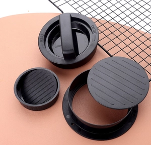 Détail du set de presse à burger noir avec bases texturées sur un tapis de cuisine rose