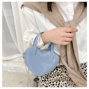 Close-up of heart-shaped light blue jelly bag with golden chain strap and shiny finish