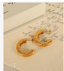 Detailed macro shot of vintage gold hammered texture C-shape chunky hoop earrings