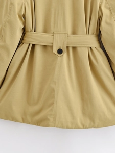 Close-up of waist belt detail and buttoned loop on the khaki trench coat's back