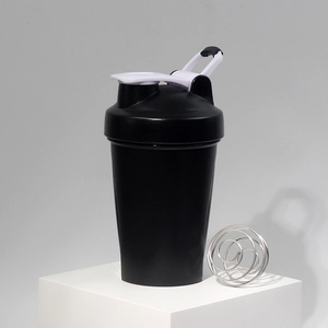 Detail of black sports protein shaker bottle with metal mixing ball on display stand