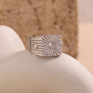 Macro shot of silver textured wide band ring with heart-shaped crystal centerpiece