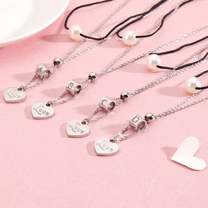 Collier cœur multicouche avec perles et lettres A-D sur fond rose texturé