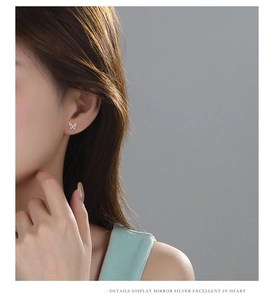 Close-up of minimalist silver butterfly stud earring on model showing elegant mirror finish